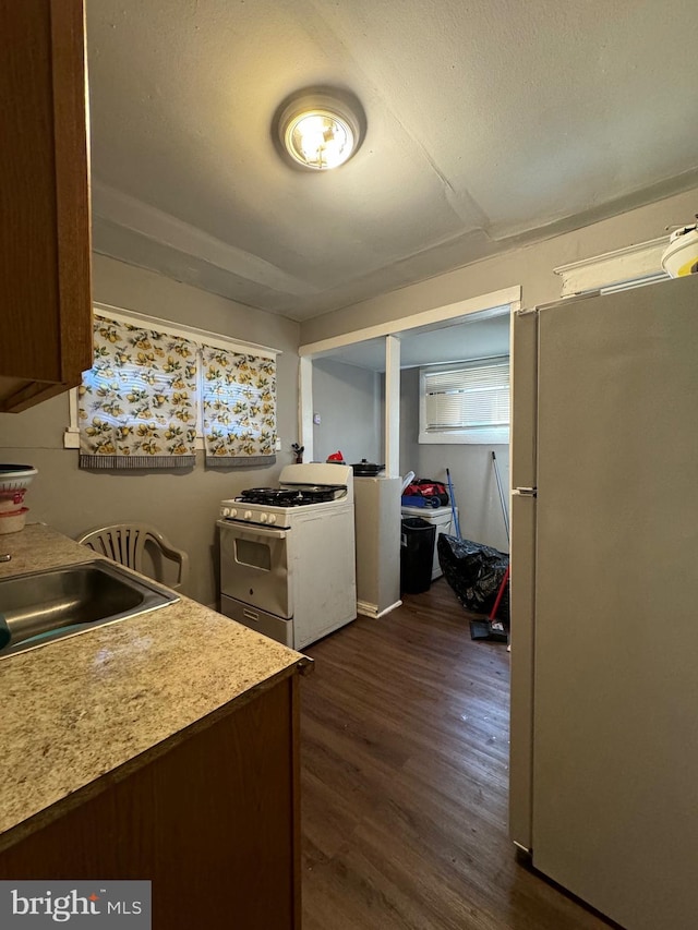 kitchen featuring a textured ceiling, white appliances, dark wood-type flooring, and sink