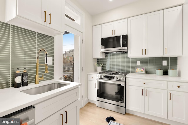 kitchen with backsplash, sink, white cabinetry, and stainless steel appliances