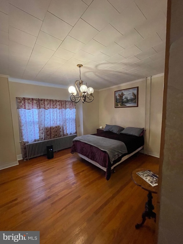 unfurnished bedroom with crown molding, radiator heating unit, a notable chandelier, and hardwood / wood-style flooring