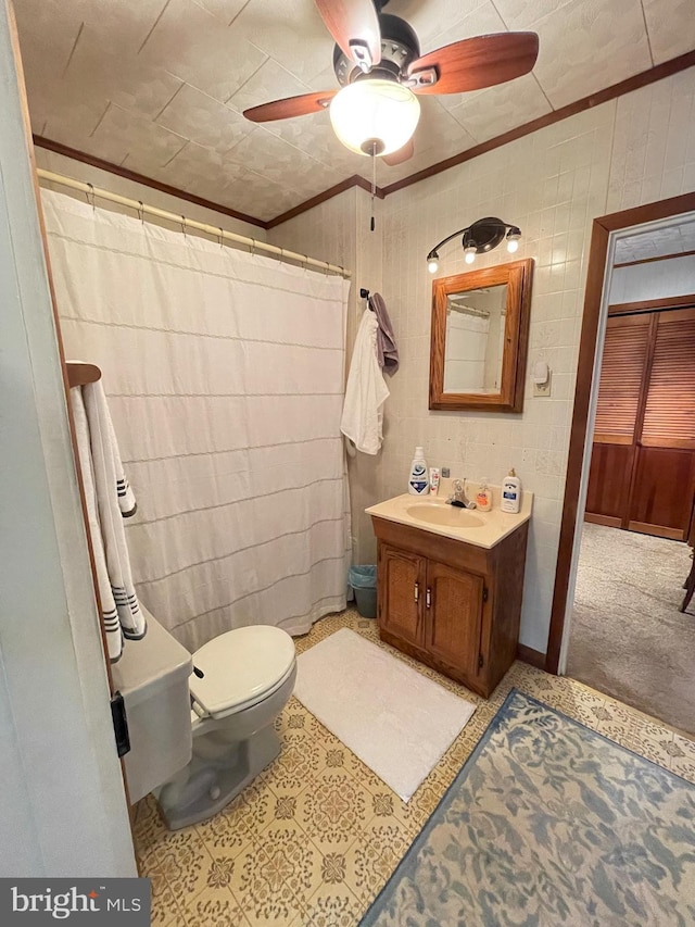 bathroom featuring curtained shower, ceiling fan, toilet, vanity, and ornamental molding