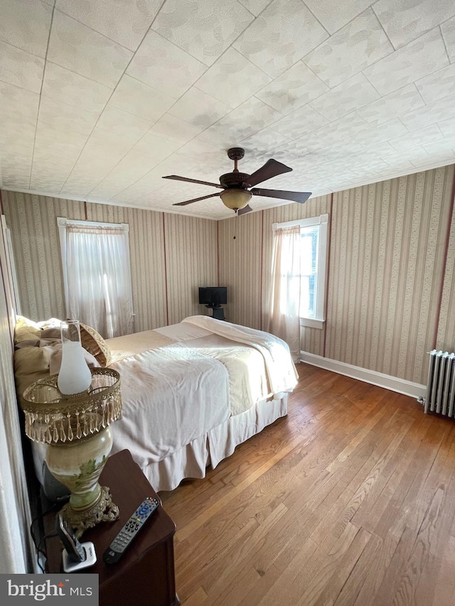 bedroom featuring ceiling fan, hardwood / wood-style floors, and radiator heating unit