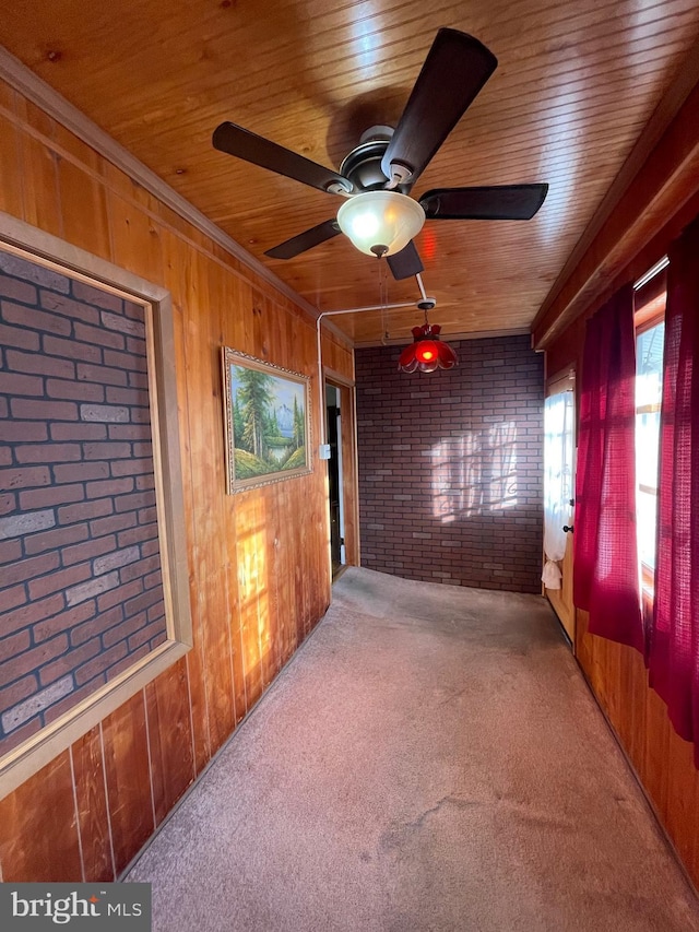 spare room featuring carpet, wood walls, ceiling fan, wood ceiling, and brick wall