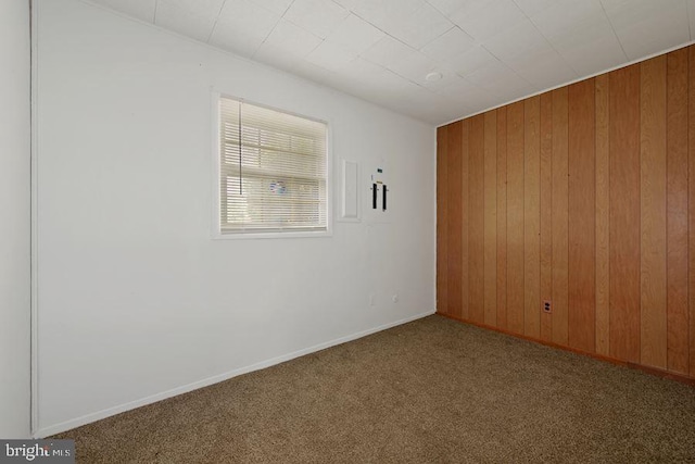 empty room with carpet floors and wood walls