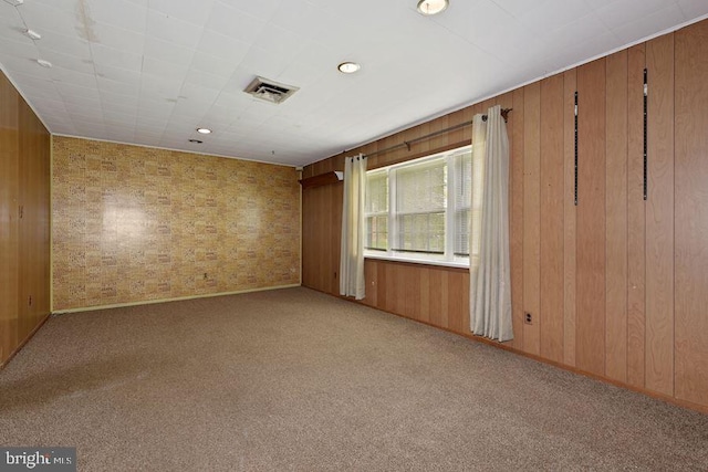 unfurnished room featuring wooden walls and light colored carpet