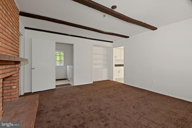 unfurnished living room with dark carpet, a fireplace, built in shelves, beamed ceiling, and independent washer and dryer