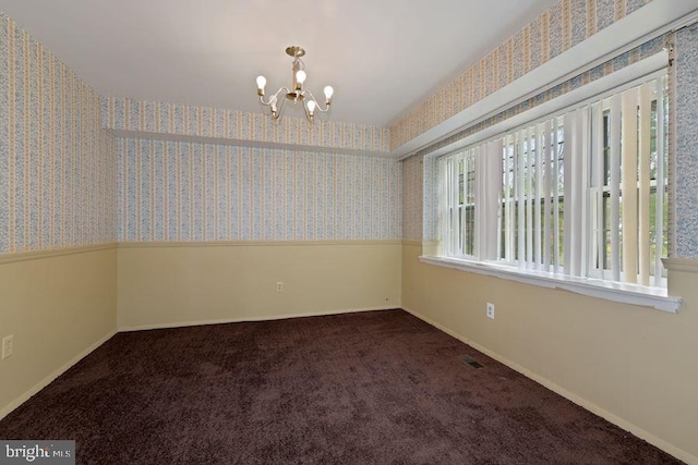 carpeted empty room with a chandelier