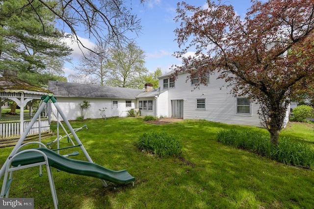 rear view of property with a gazebo, a playground, and a yard