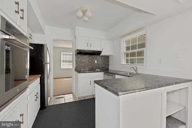 kitchen with kitchen peninsula, sink, black appliances, white cabinetry, and plenty of natural light