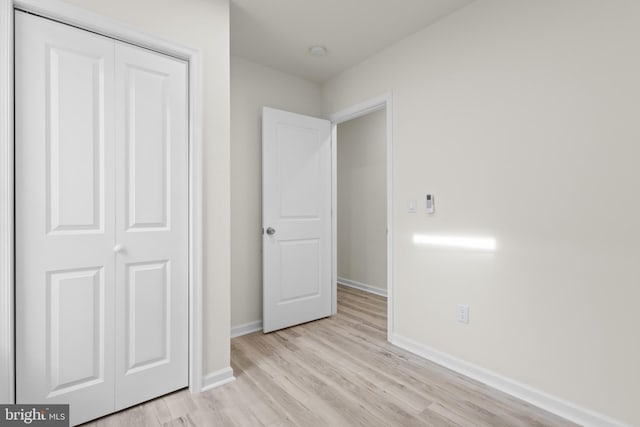 unfurnished bedroom with light hardwood / wood-style flooring and a closet