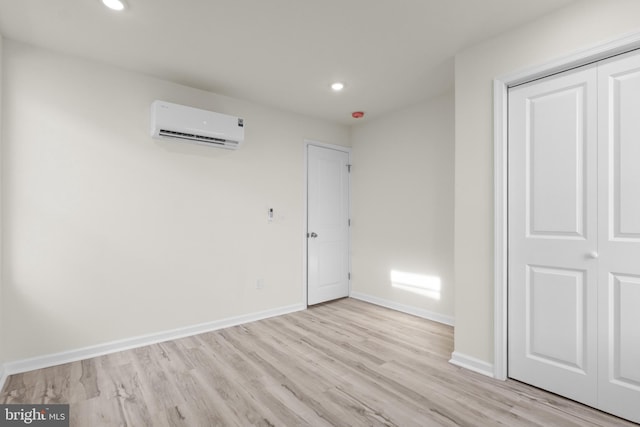 unfurnished bedroom featuring light hardwood / wood-style floors, a wall unit AC, and a closet