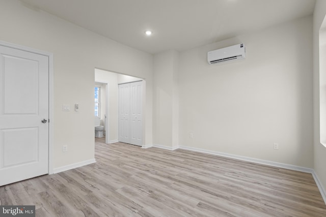 spare room with light wood-type flooring and an AC wall unit