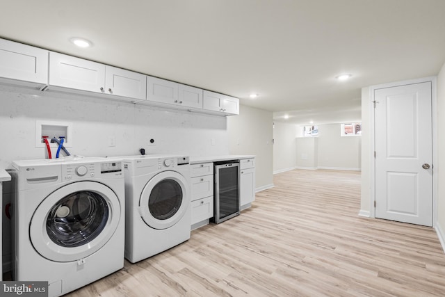 laundry area with washer and clothes dryer, wine cooler, and light hardwood / wood-style flooring