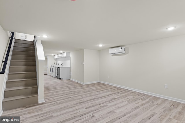 basement with a wall mounted air conditioner, indoor bar, separate washer and dryer, and light hardwood / wood-style flooring