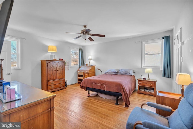 bedroom featuring ceiling fan, light hardwood / wood-style floors, and multiple windows