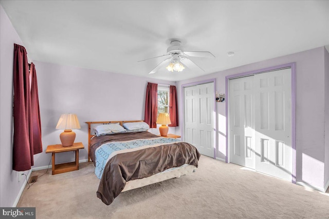 bedroom featuring multiple closets, ceiling fan, and light carpet