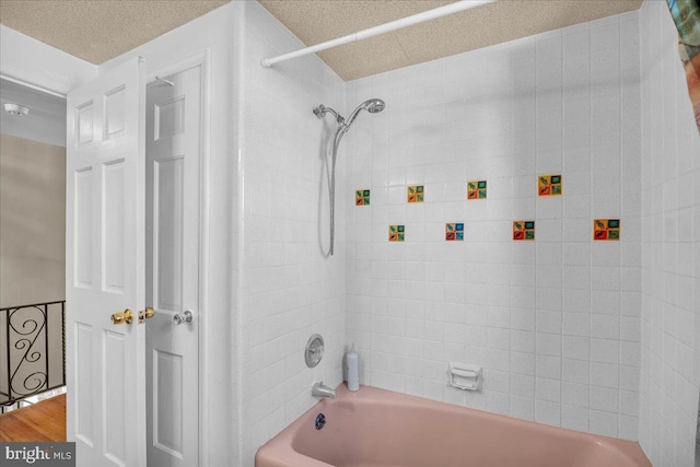 bathroom with hardwood / wood-style floors, a textured ceiling, and tiled shower / bath