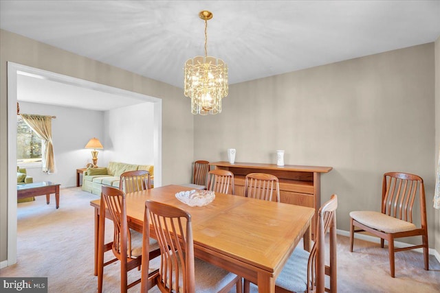 dining room with light carpet and a notable chandelier