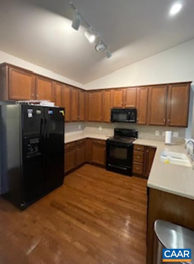 kitchen with sink, dark hardwood / wood-style flooring, lofted ceiling, and black appliances