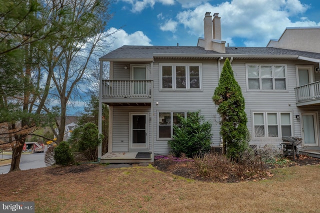 rear view of property with a lawn and a balcony