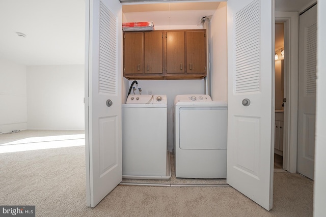 clothes washing area with washer and dryer, light colored carpet, and cabinets