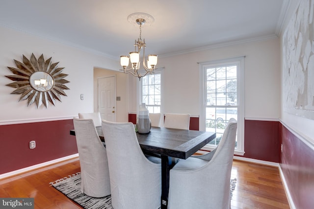 dining room featuring hardwood / wood-style flooring, an inviting chandelier, and crown molding