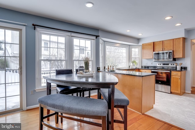 kitchen with dark stone countertops, sink, appliances with stainless steel finishes, and light hardwood / wood-style flooring