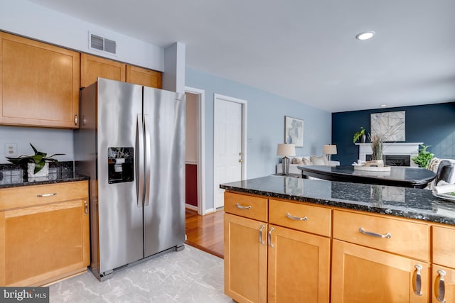 kitchen with dark stone countertops and stainless steel fridge