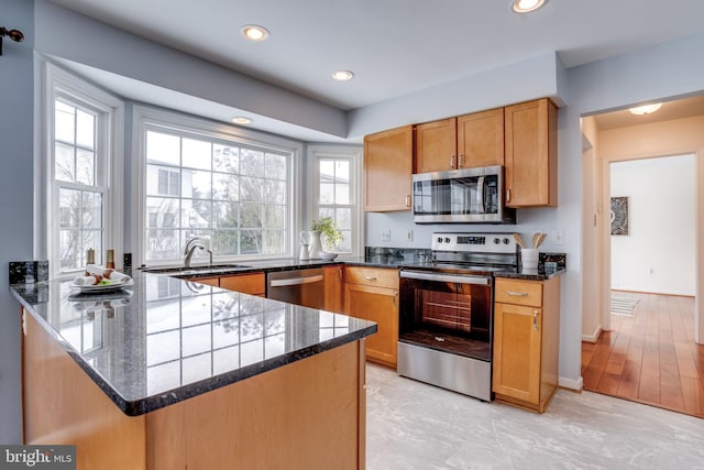 kitchen with kitchen peninsula, sink, dark stone countertops, and stainless steel appliances