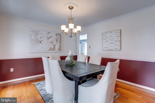 dining area featuring ornamental molding, light hardwood / wood-style floors, and a notable chandelier