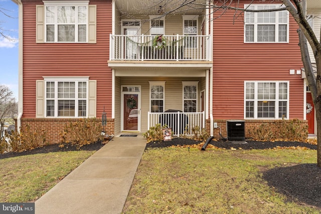 multi unit property with a front lawn, a balcony, and central AC