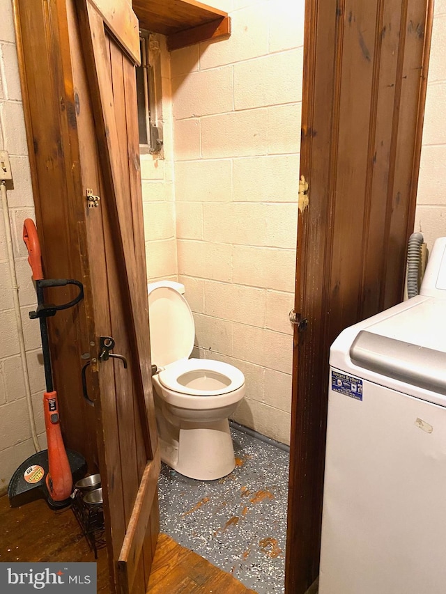 bathroom featuring washer / dryer, toilet, and wood-type flooring