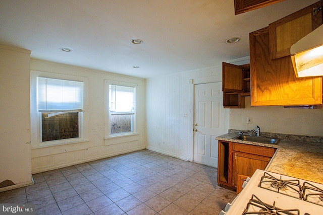 kitchen with light tile patterned flooring, wood walls, and sink