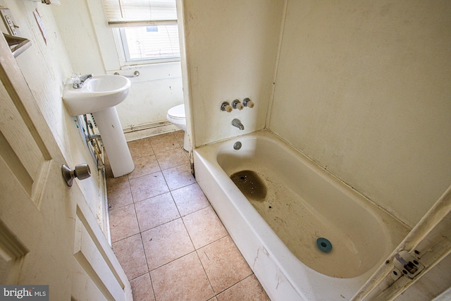 bathroom with tile patterned floors, sink, toilet, and a tub to relax in