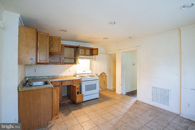 kitchen with light tile patterned floors, sink, and gas range gas stove