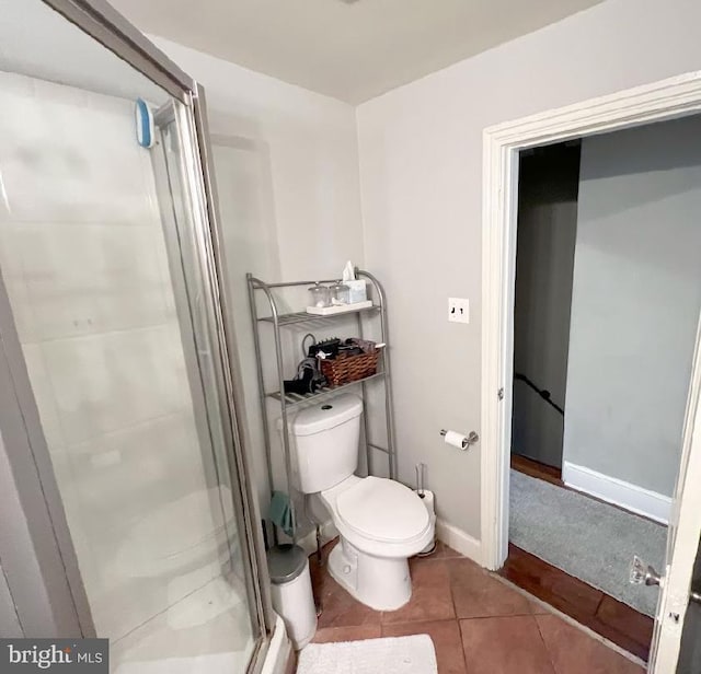 bathroom with tile patterned flooring, a shower with door, and toilet