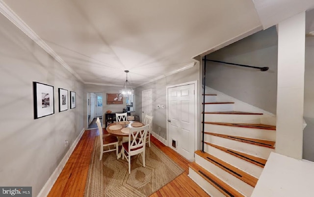 dining room featuring crown molding, hardwood / wood-style floors, and an inviting chandelier