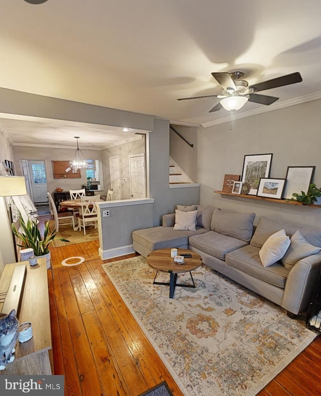 living room with ornamental molding, ceiling fan with notable chandelier, and hardwood / wood-style flooring