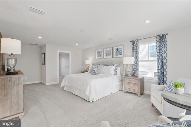 bedroom with light colored carpet, a walk in closet, and a closet