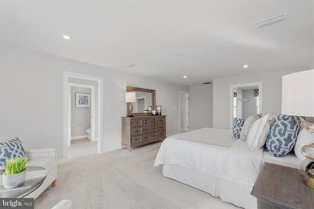 bedroom with connected bathroom and light carpet