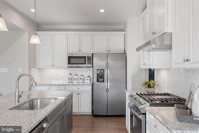 kitchen with pendant lighting, sink, light stone counters, and stainless steel appliances