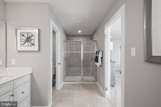 bathroom with tile patterned flooring, vanity, toilet, and a shower with shower door