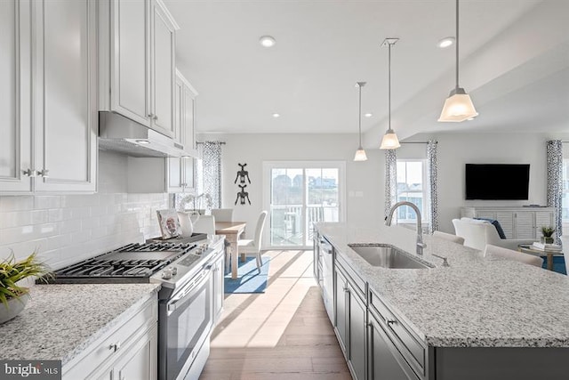 kitchen featuring a kitchen island with sink, sink, light hardwood / wood-style flooring, gas stove, and white cabinetry