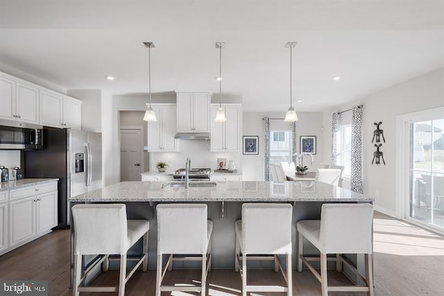 kitchen with hanging light fixtures, a center island with sink, stainless steel appliances, and sink