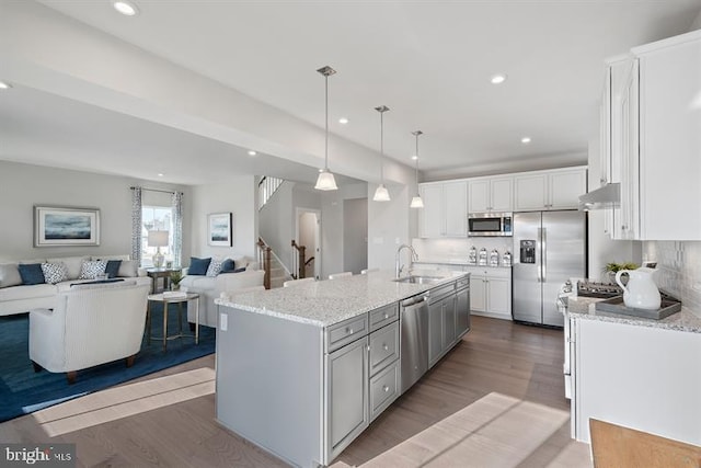 kitchen featuring appliances with stainless steel finishes, sink, pendant lighting, a center island with sink, and white cabinetry