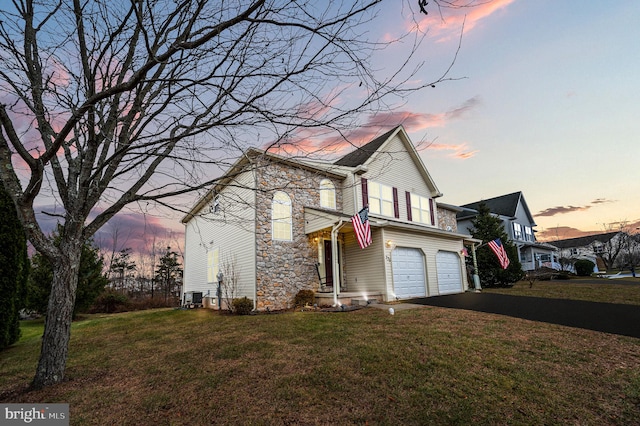 view of front of home featuring a garage, a yard, and central AC