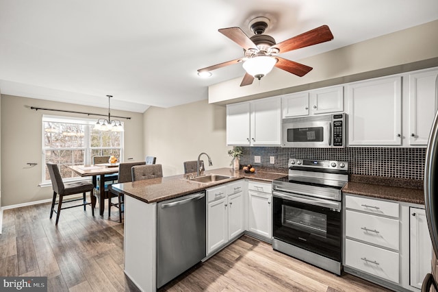 kitchen with white cabinets, sink, appliances with stainless steel finishes, light hardwood / wood-style floors, and kitchen peninsula