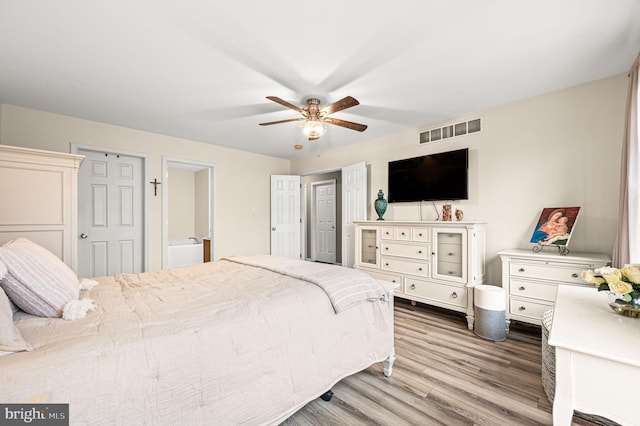 bedroom with hardwood / wood-style flooring, ceiling fan, and connected bathroom