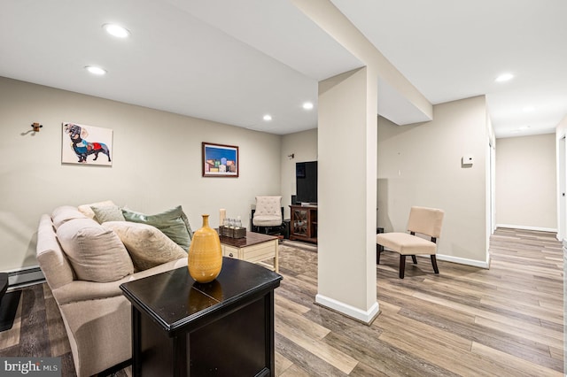 living room featuring a baseboard heating unit and hardwood / wood-style flooring