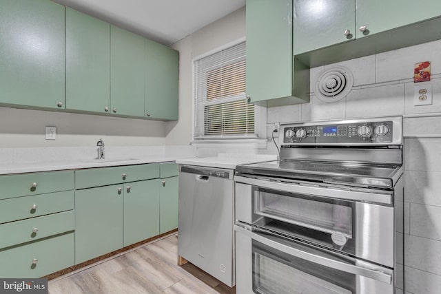 kitchen featuring sink, stainless steel appliances, light hardwood / wood-style floors, and green cabinetry