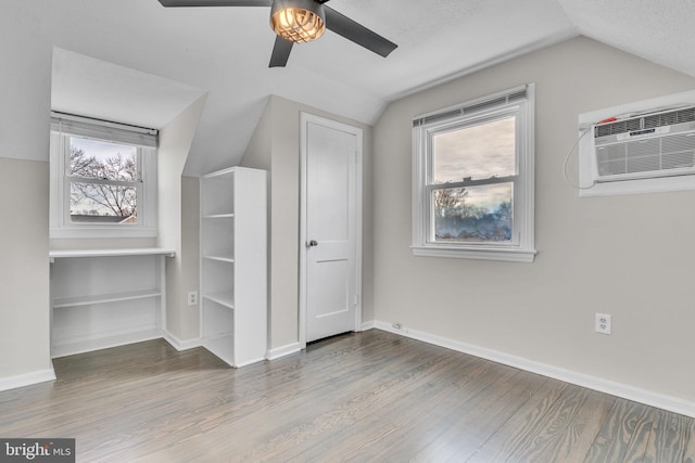 bonus room featuring hardwood / wood-style flooring, an AC wall unit, vaulted ceiling, and a wealth of natural light